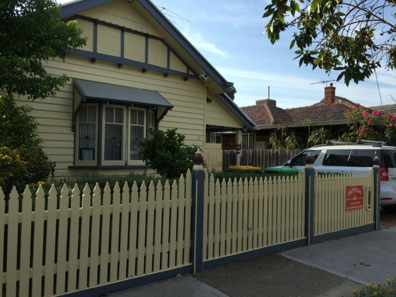 A white picket fence surrounds a yellow house