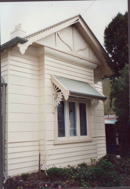 A small white house with a window and a canopy