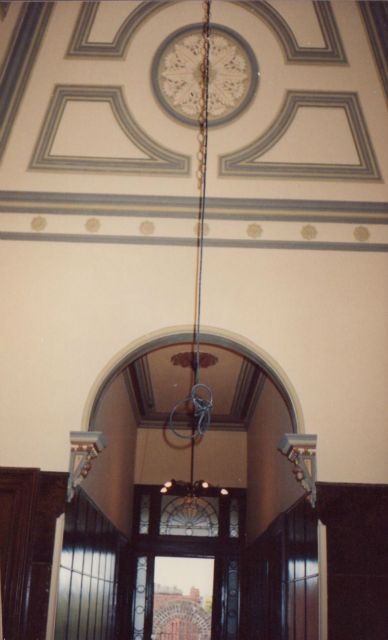 A clock hangs from the ceiling of a building
