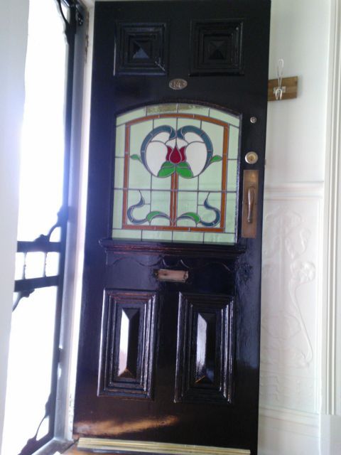 A black door with a stained glass window with a flower on it