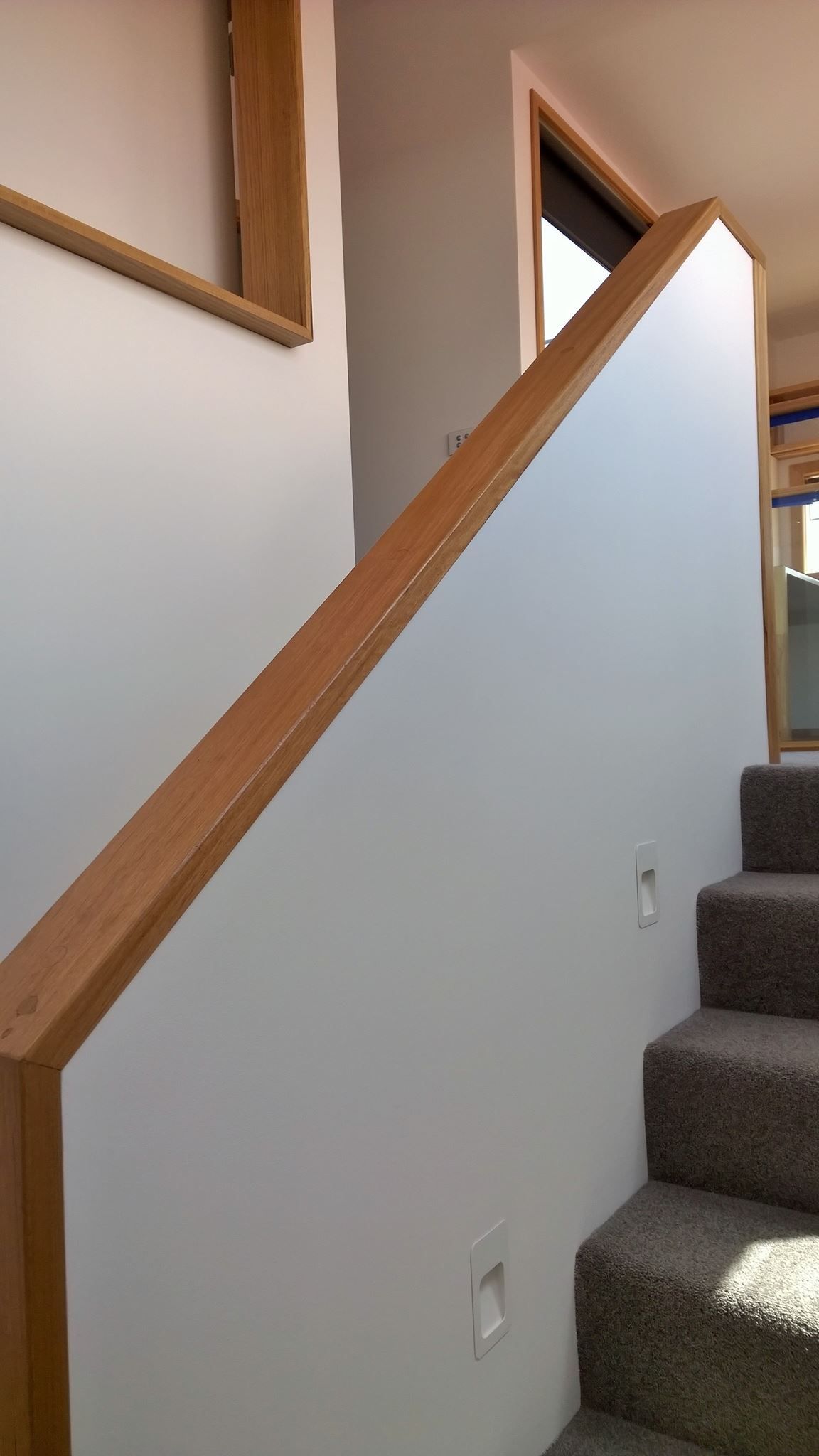 A staircase with a wooden railing and carpeted steps