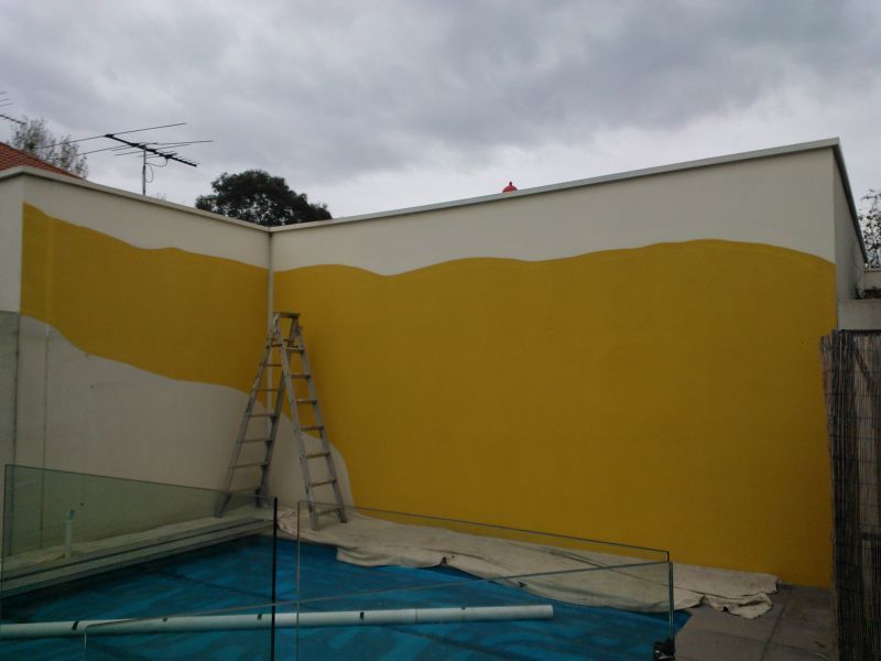 A yellow and white wall with a ladder in front of it