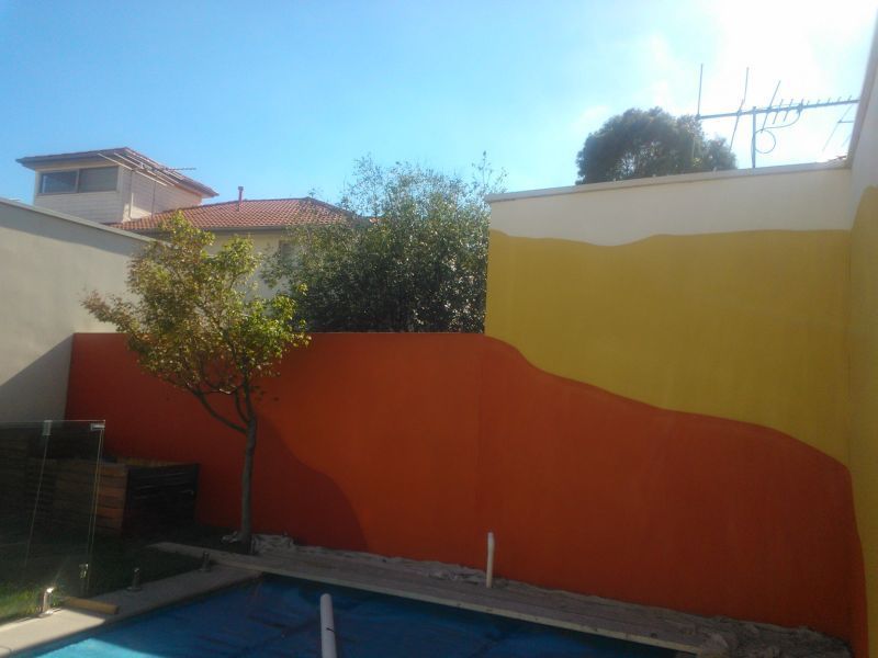 A swimming pool with a yellow and orange wall behind it