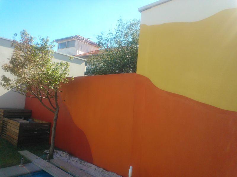 An orange and yellow wall with a tree in front of it