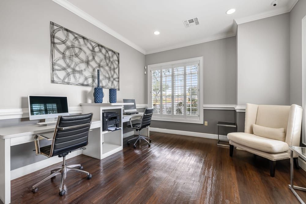 Apartment business center with two desks, chairs, a computer, and a chair at Marquis at The RIM in Northwest San Antonio, TX.
