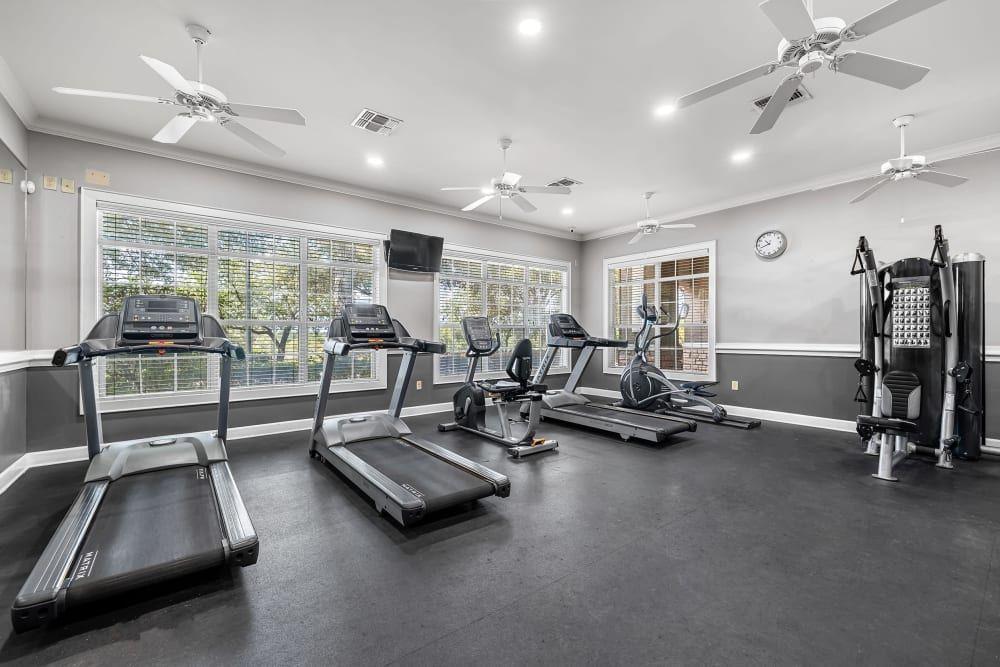 A fitness center with treadmills, exercise bikes, and a ceiling fan at Marquis at The RIM in Northwest San Antonio, TX.