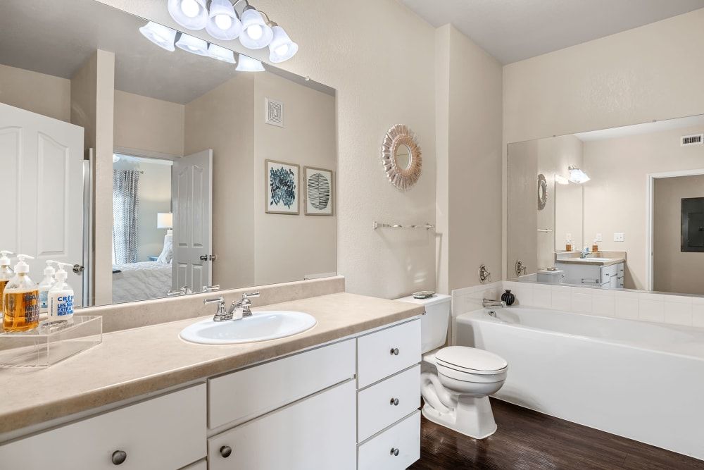 Resort-style bathroom with a sink, toilet, tub and mirror at Marquis at The RIM in Northwest San Antonio, TX.