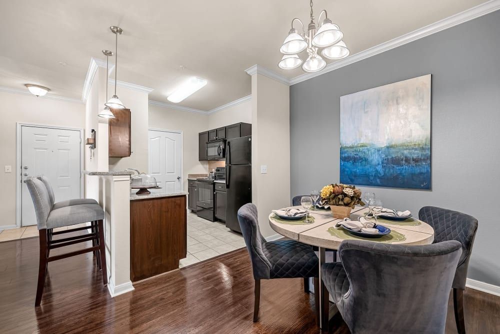 Apartment dining room with a table and chairs and a kitchen in the background at Marquis at The RIM in Northwest San Antonio, TX.