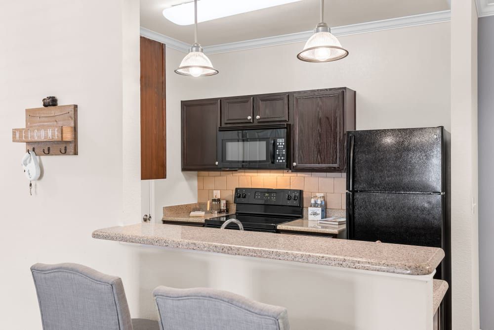 A kitchen with a refrigerator, stove, microwave, and sink at Marquis at The RIM in Northwest San Antonio, TX.