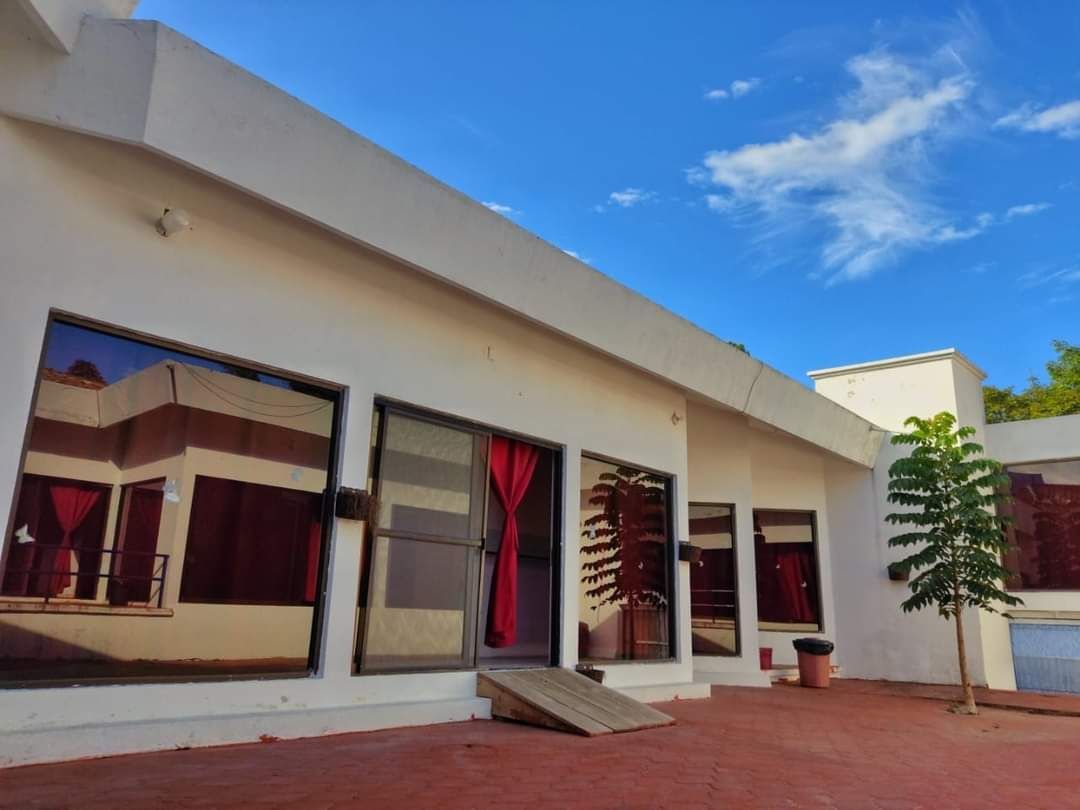 Un edificio blanco con muchas ventanas y un árbol frente a él.