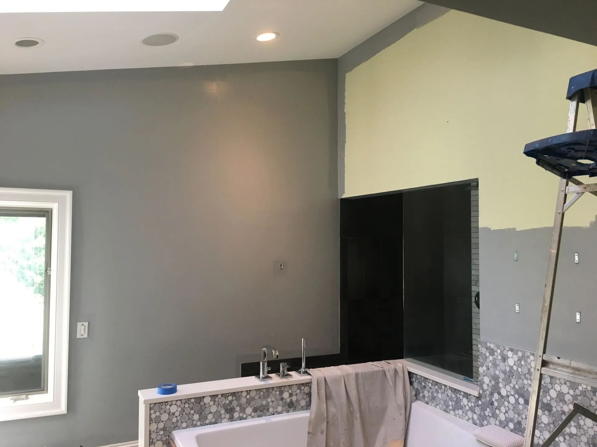 Empty kitchen under renovation with gray walls, granite counters, and a pass-through opening to another room