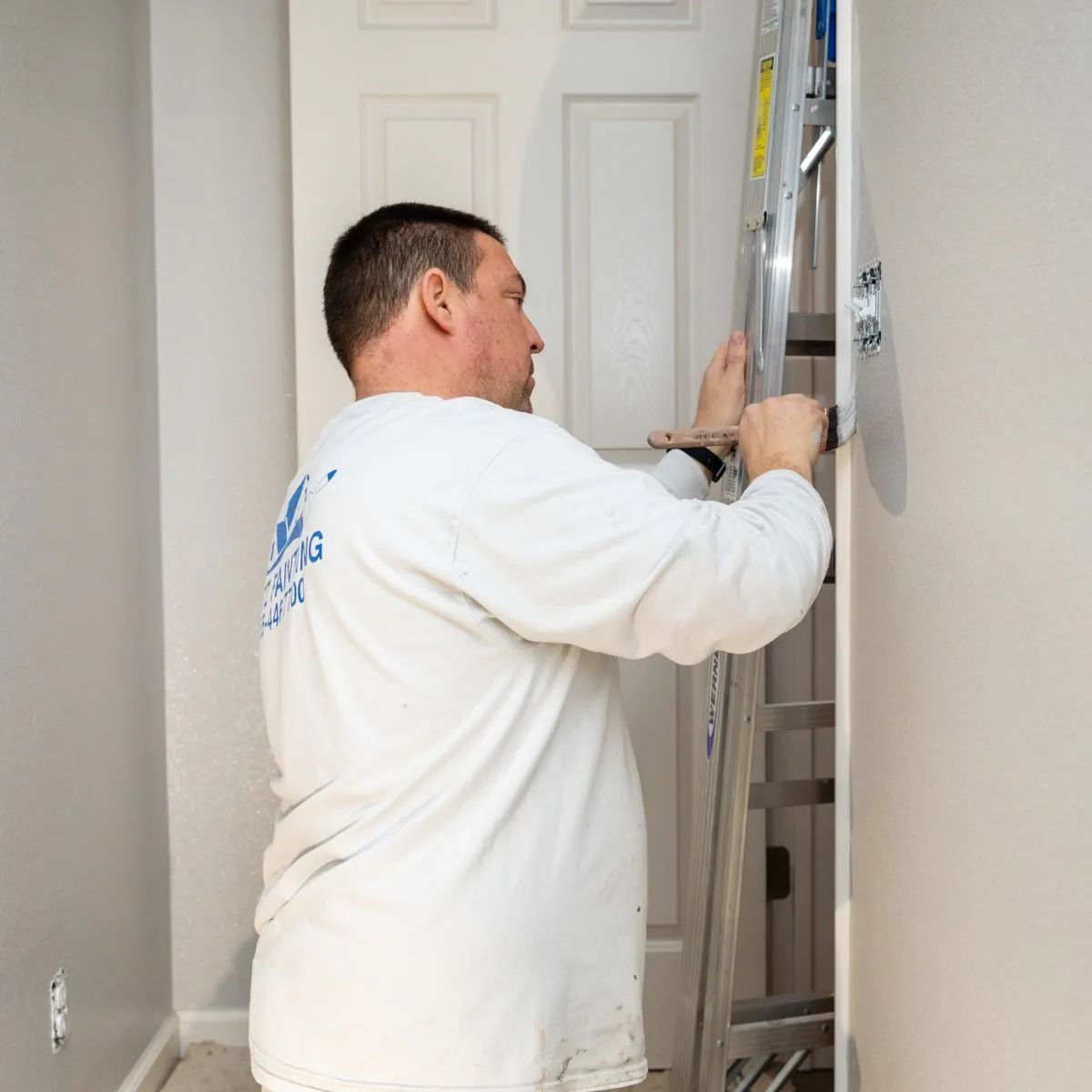 Person adjusting a wall-mounted ladder in a hallway