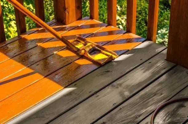 Wooden porch with a folding chair in bright orange sunlight casting striped shadows.