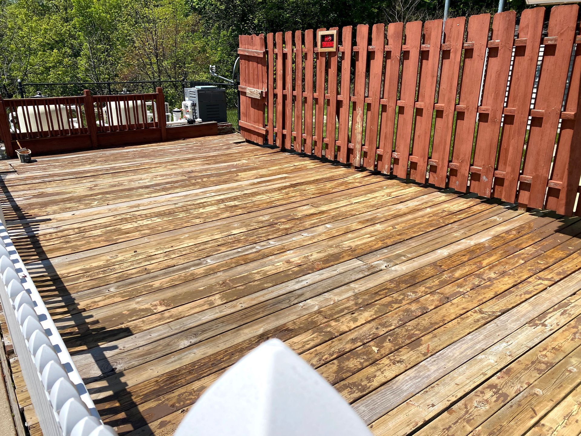 Sunlit wooden deck with a red fence and a white chair in the foreground