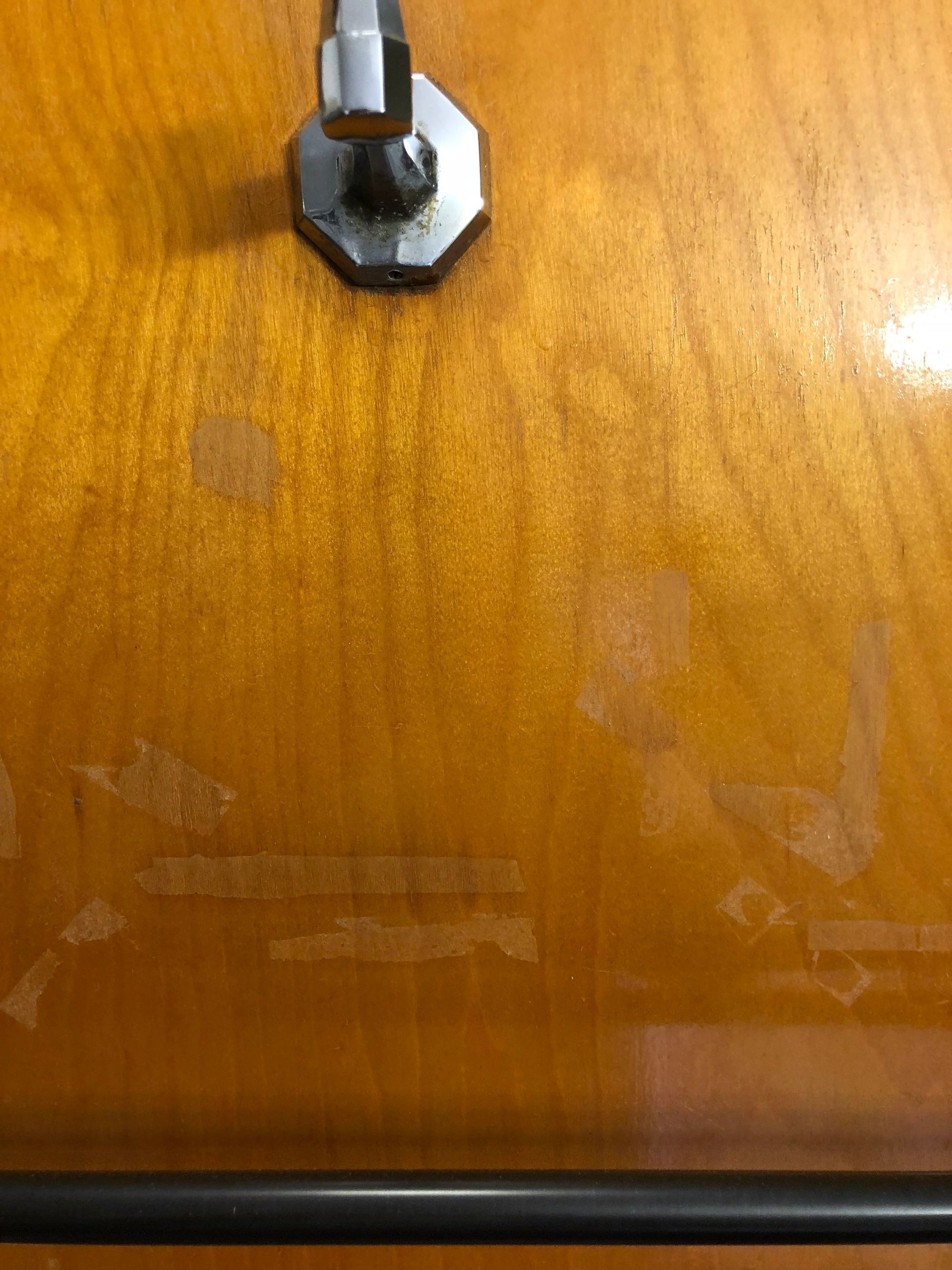 Close-up of a wooden door with a metal knob and lock hardware near the top.