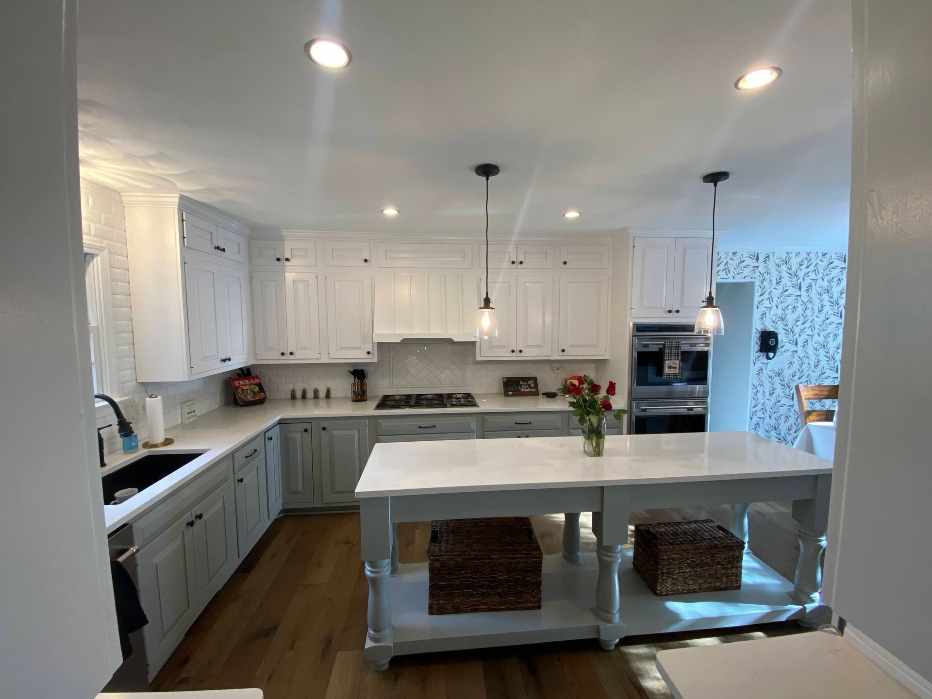 Bright white kitchen with large island, pendant lights, and woven baskets under the counter