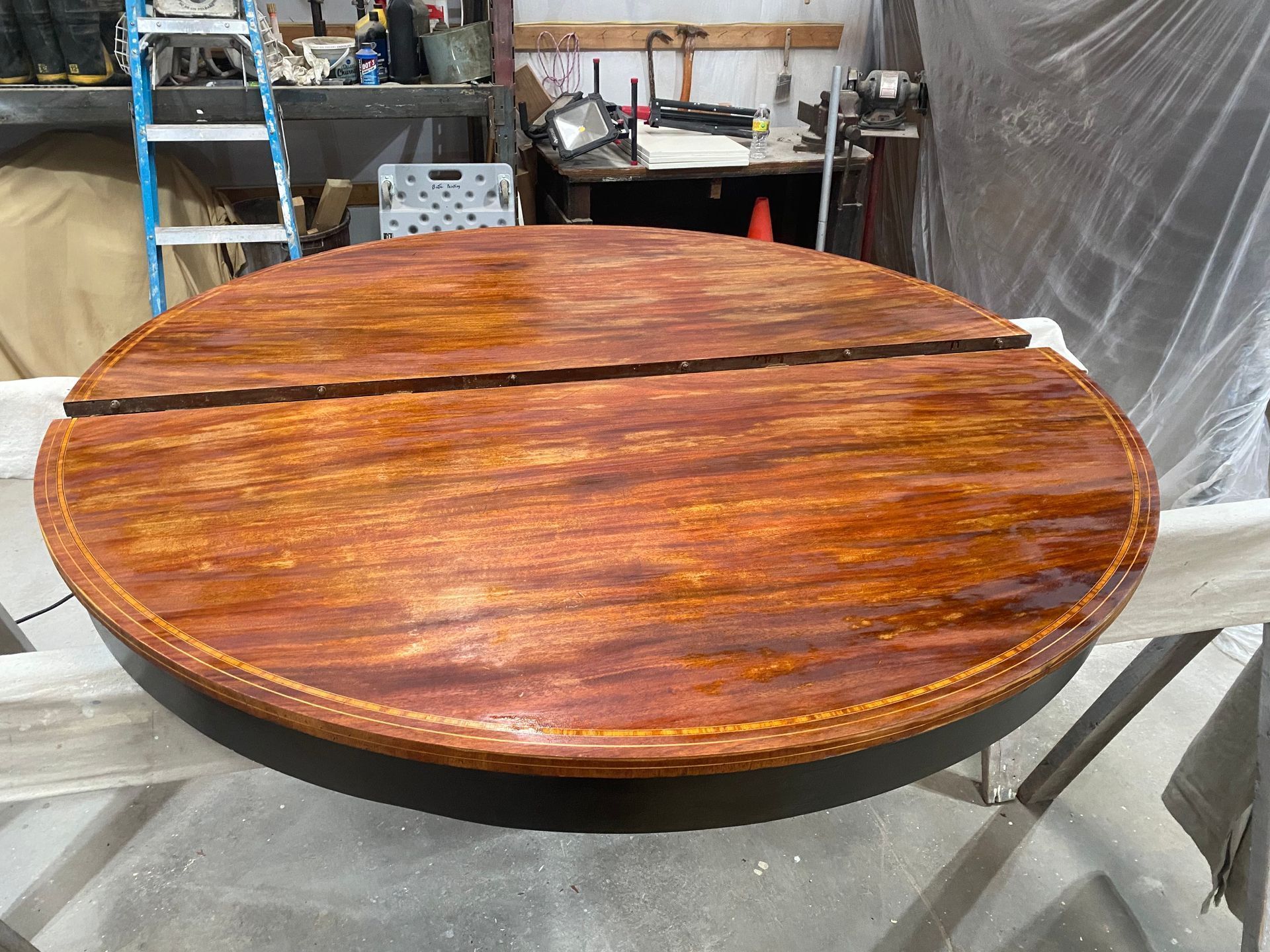 Large round wooden tabletop with a glossy finish in a workshop setting