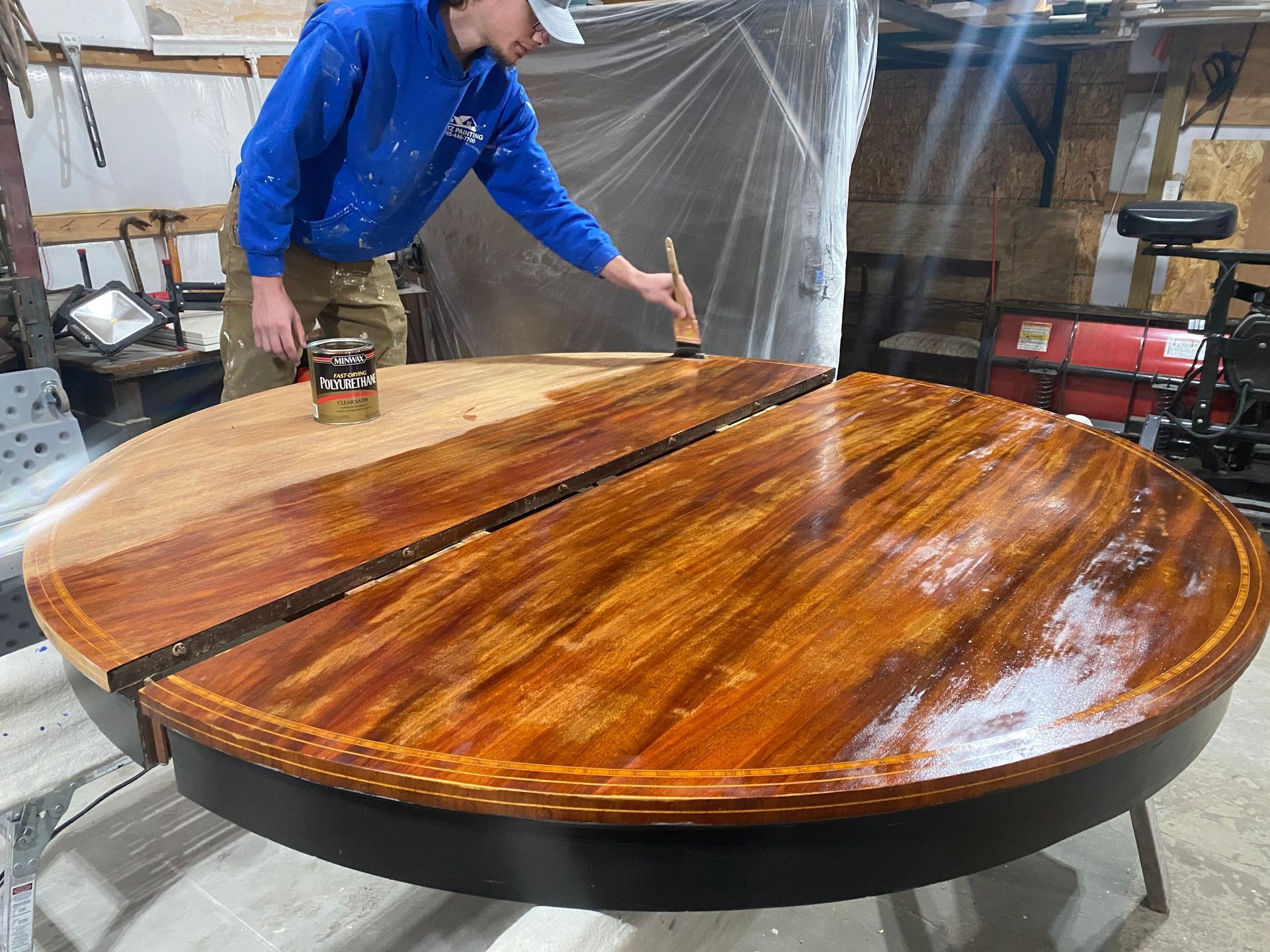 Person applying finish to a round wooden table in a workshop