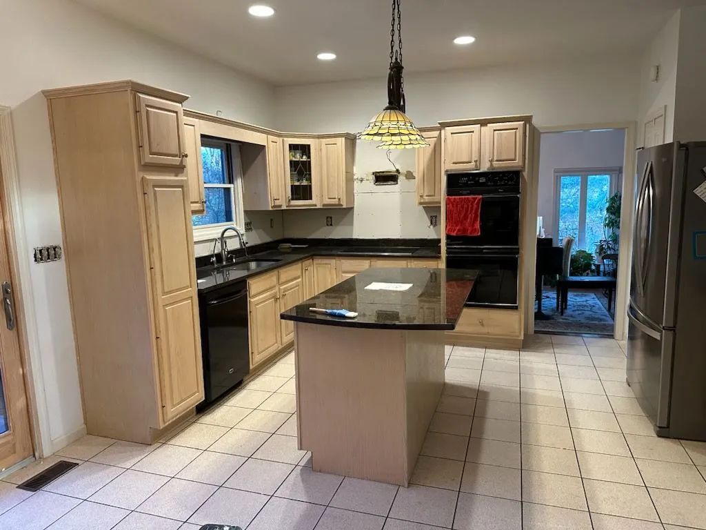 Modern kitchen with white cabinets, black countertops, island, and tiled floor