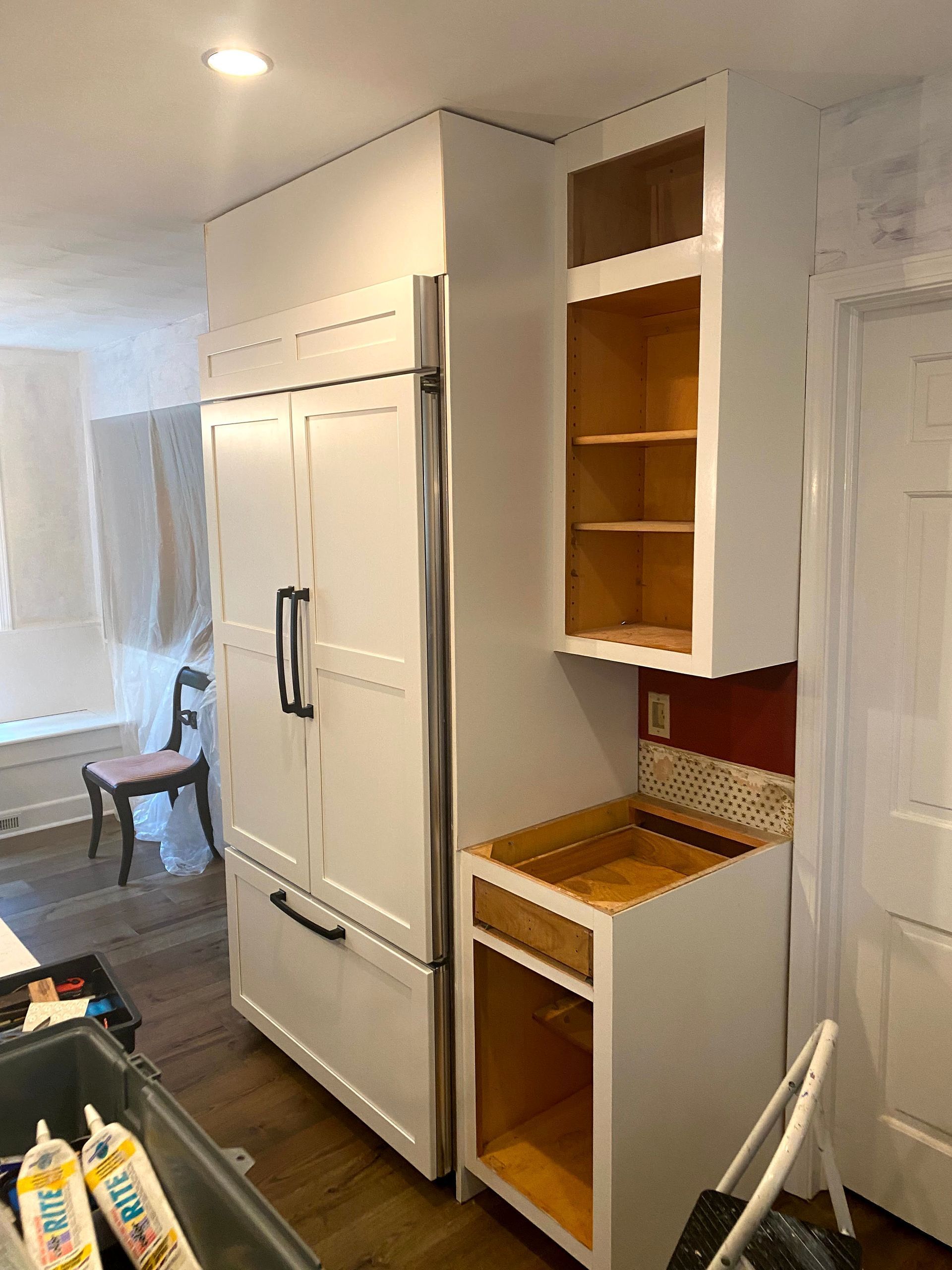 Kitchen with white cabinets, open shelves, and a large built-in refrigerator in a bright home interior