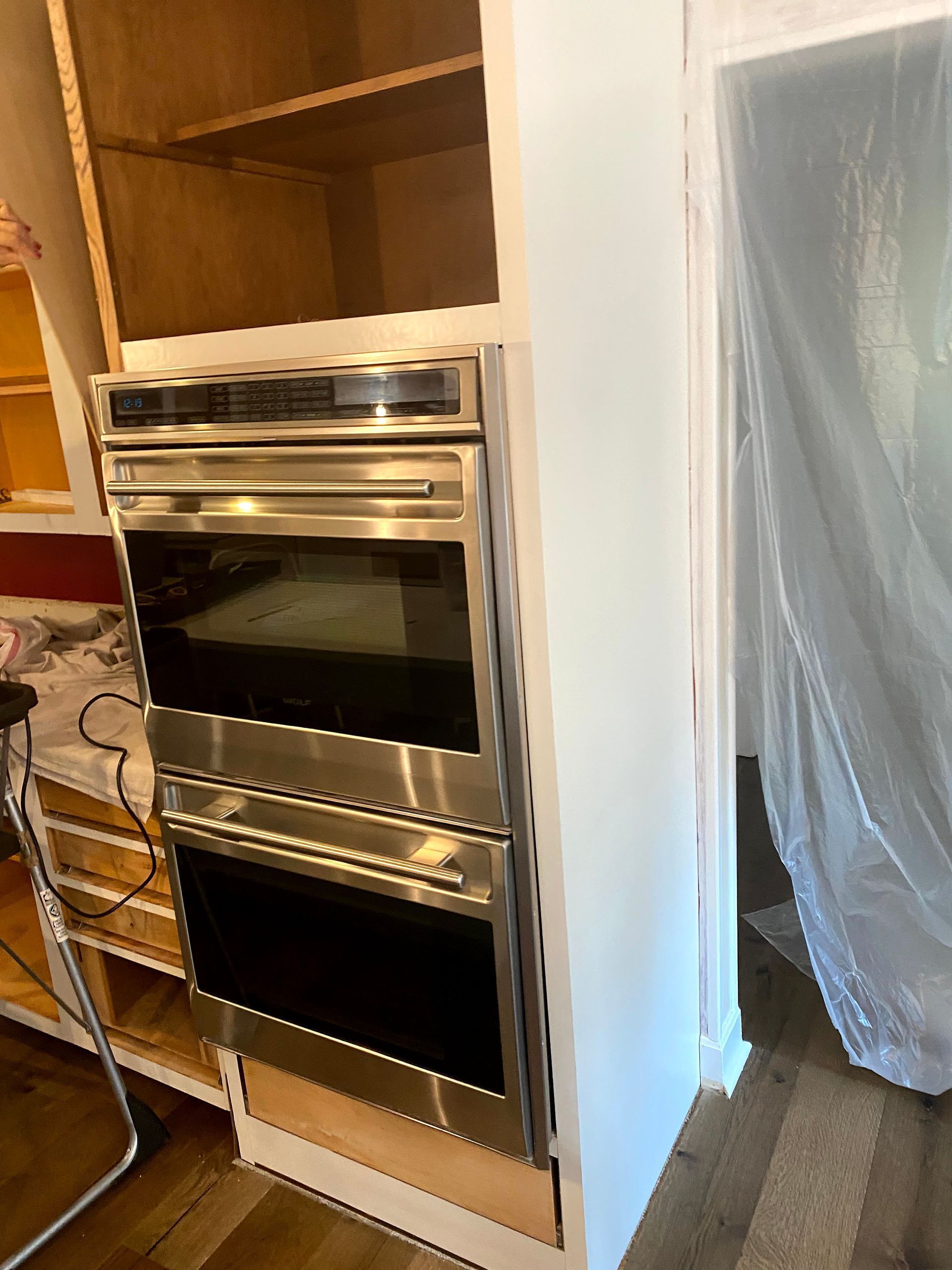 Built-in stainless steel double oven in an unfinished kitchen cabinet opening