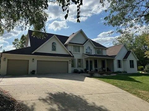 Suburban house with a two-car garage, front porch, and tree-shaded driveway