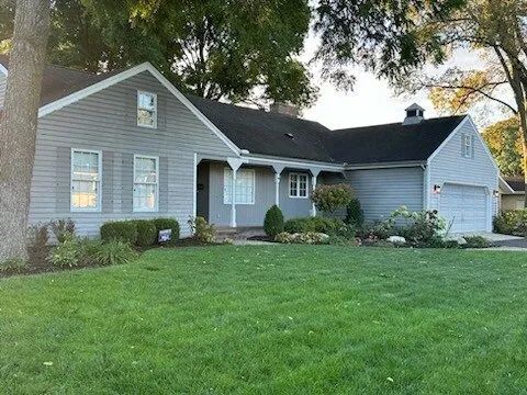 Gray suburban house with white trim and a front lawn, viewed from the street