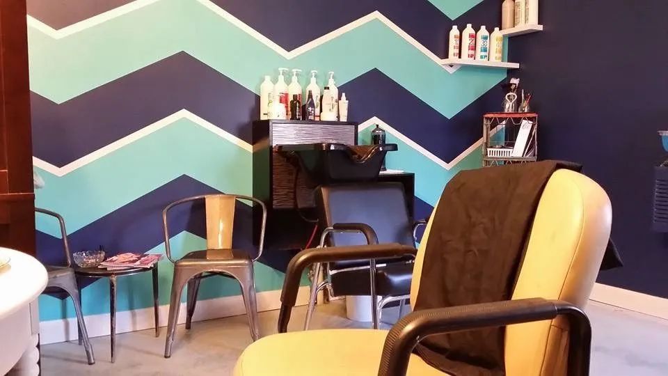 Barbershop interior with chevron wall, chairs, mirrors, and hair product shelves