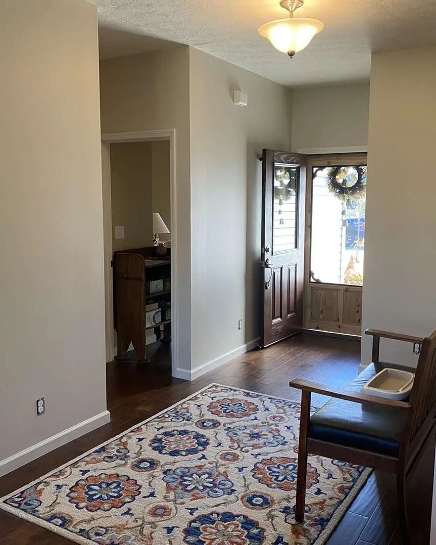Small hallway with rug, wooden chair, and front door in a softly lit home entryway