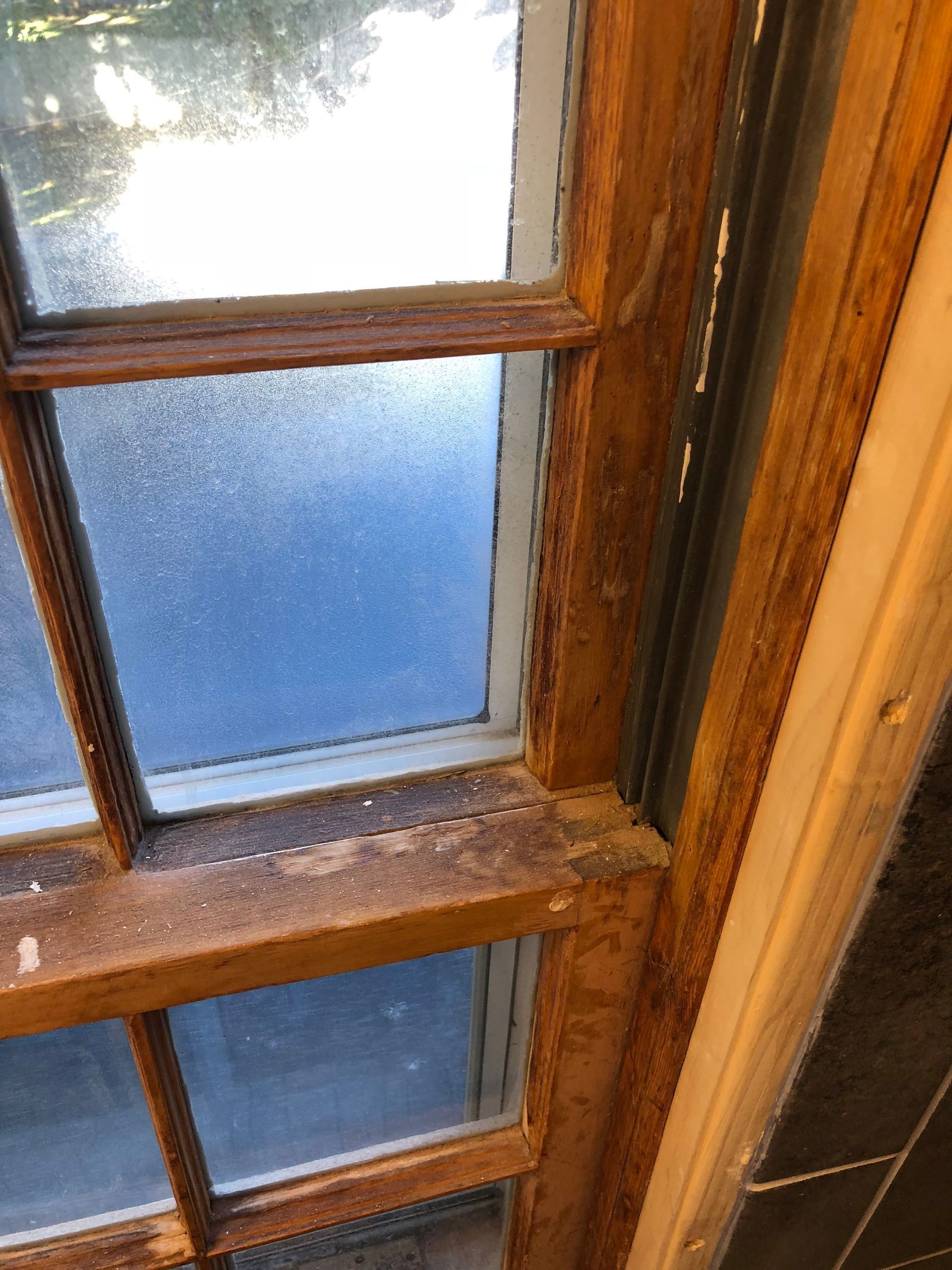 Close-up of a wooden-paned window with frosted blue glass and light shining through.