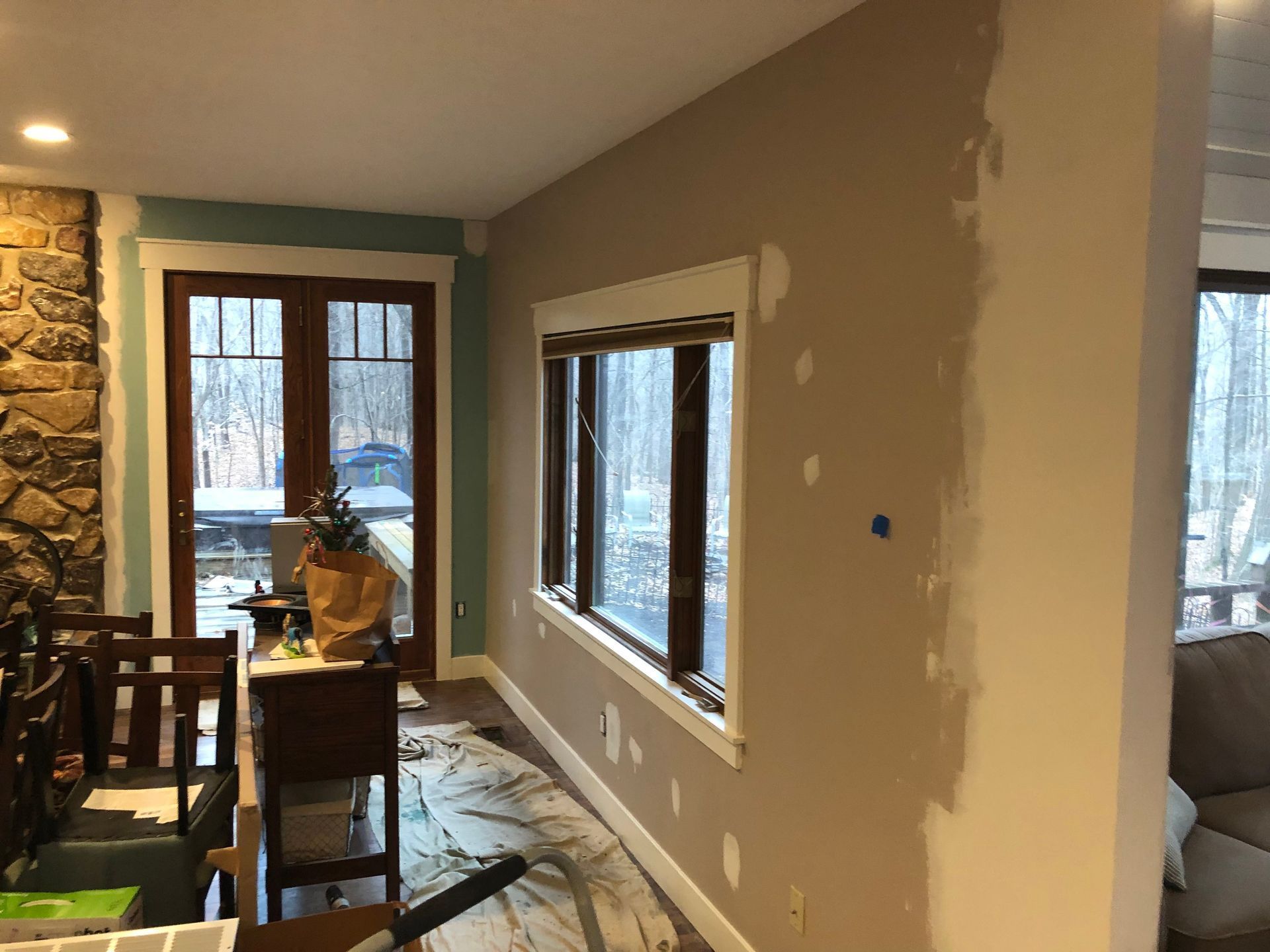 Dining room with beige walls, windows, and a table by a glass door, in a partially finished interior.