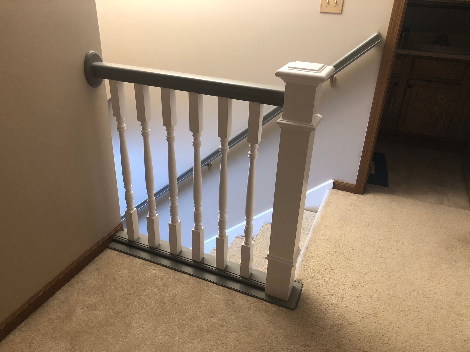 Staircase landing with white railing and beige carpet in a hallway