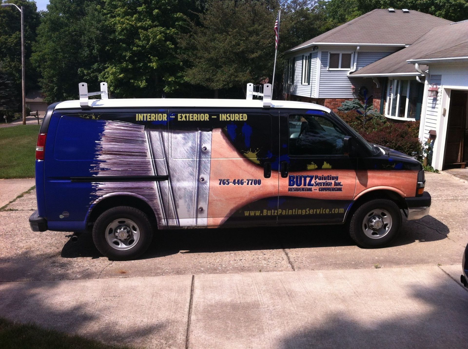 Blue and orange service van parked in a driveway, covered with promotional graphics and text.