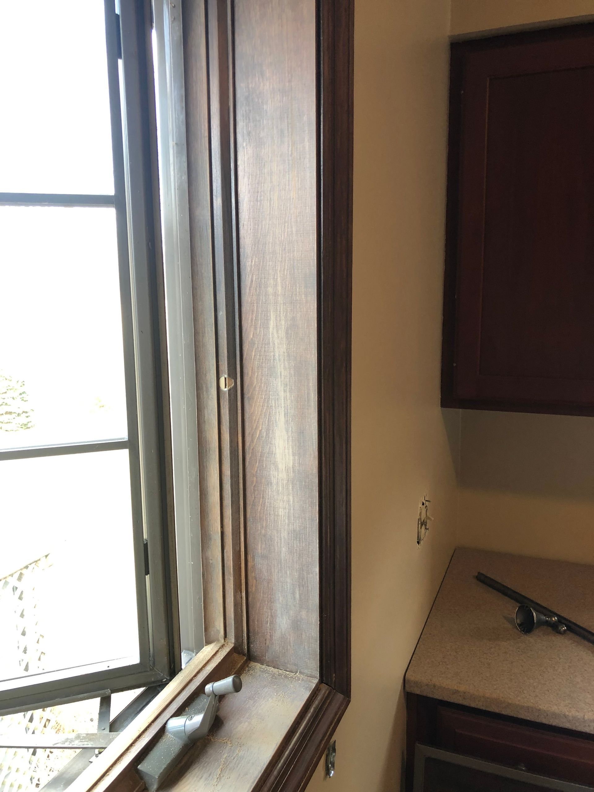 Open window beside a beige wall and countertop in a small room