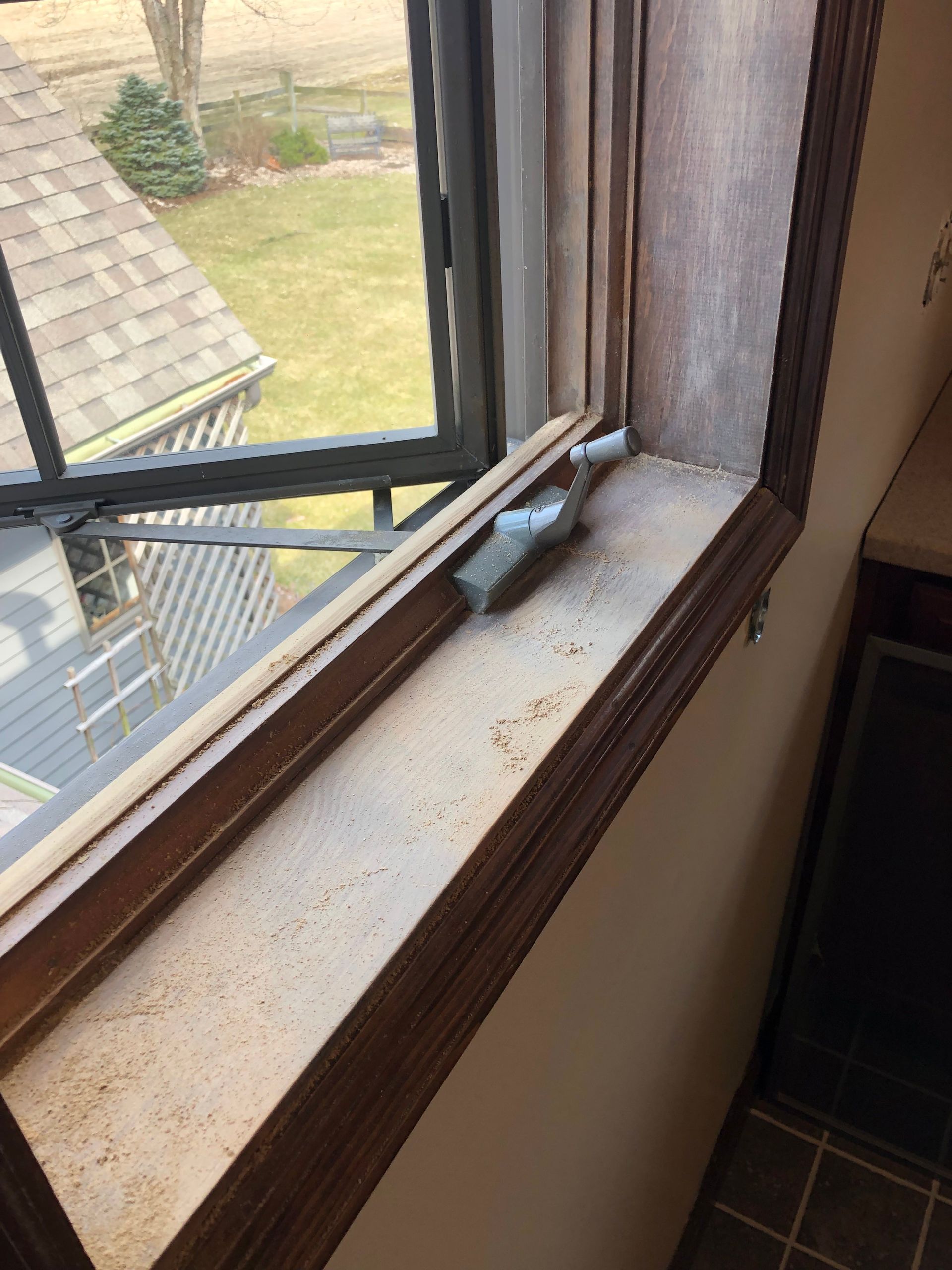 Window ledge with a small bird figurine beside a glass window and curtains