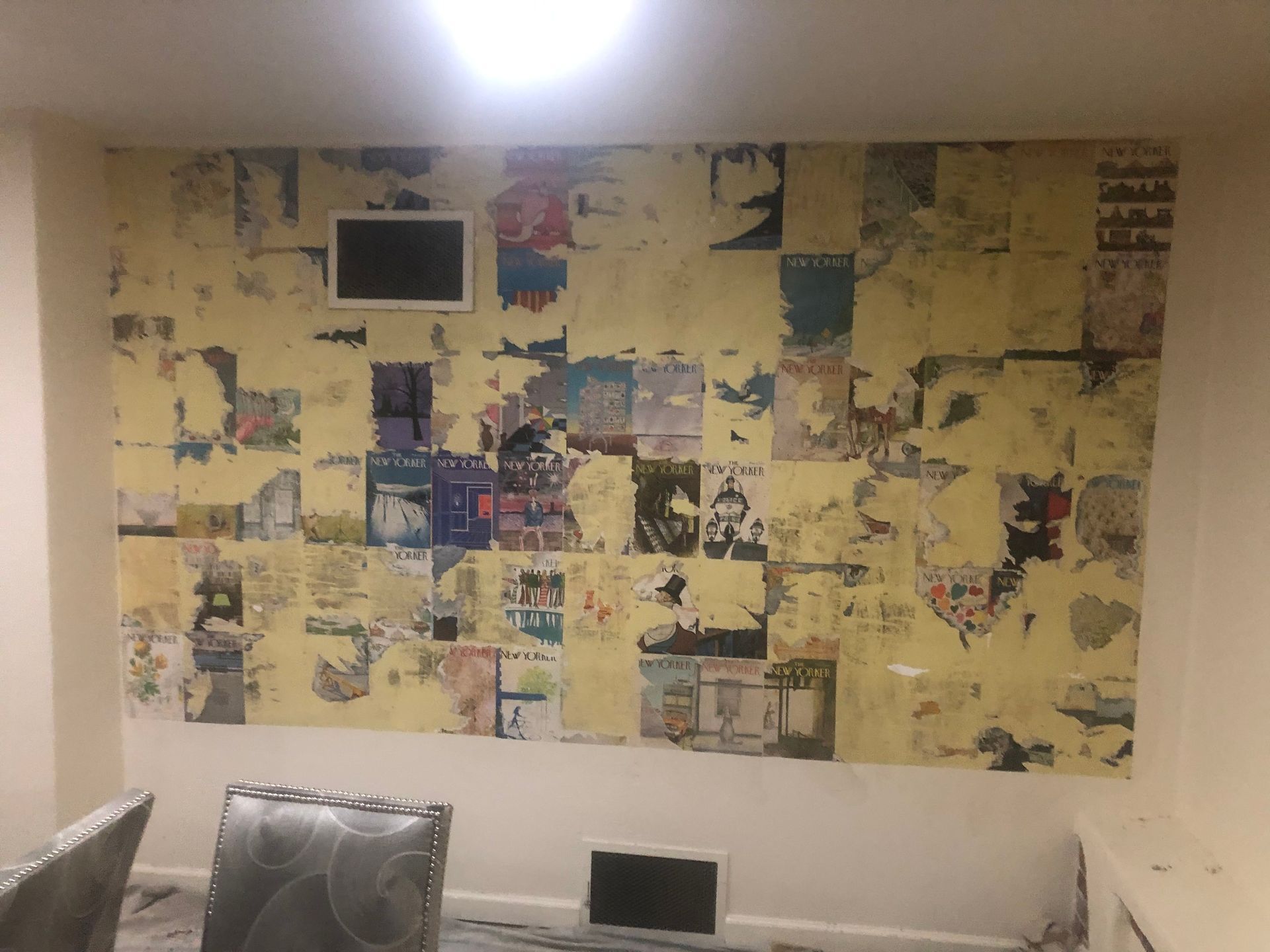 Wall mural of colorful collaged posters above a white sofa in a modern room