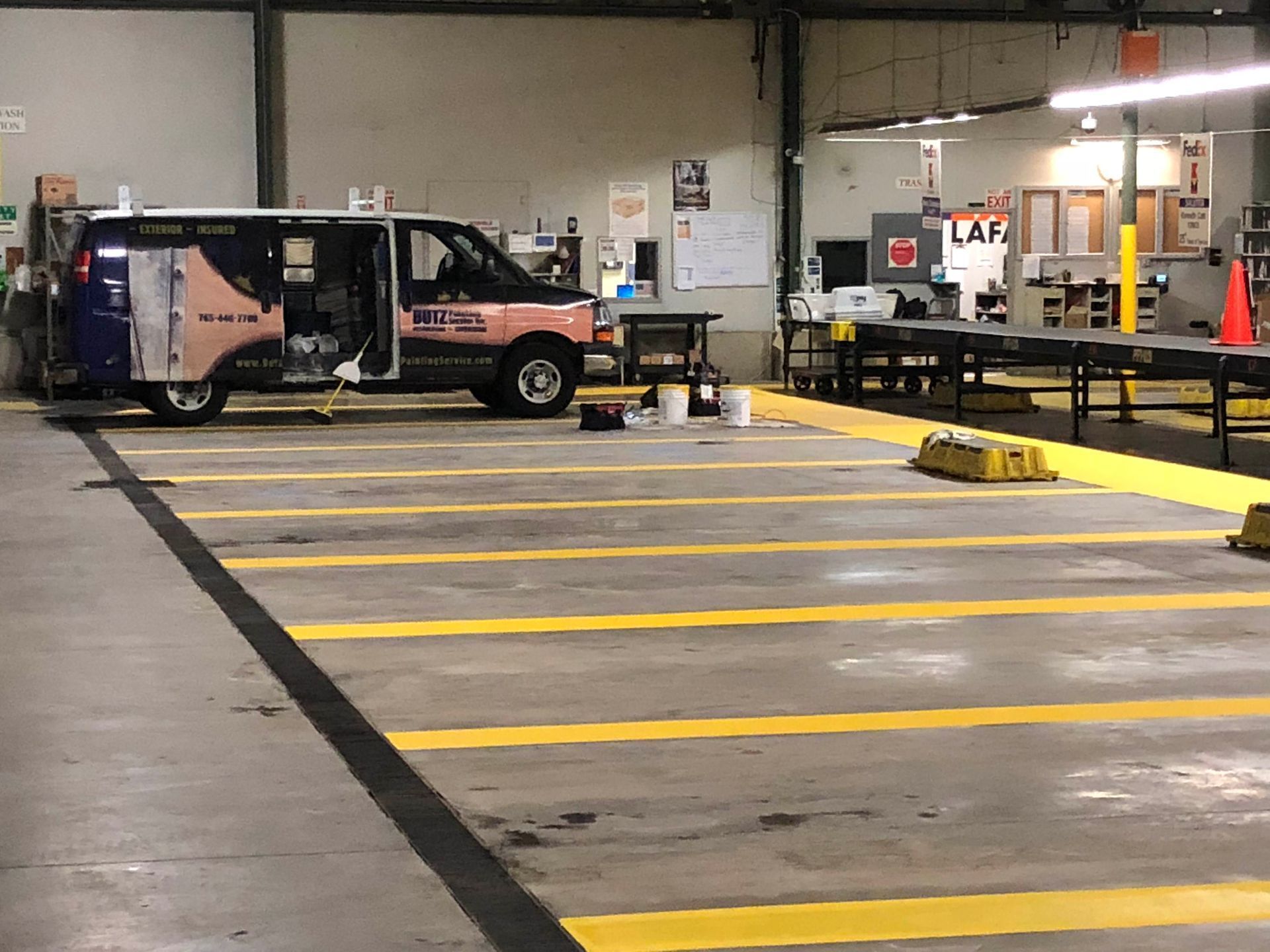 Van parked in an indoor loading bay beside yellow safety markings and dock equipment