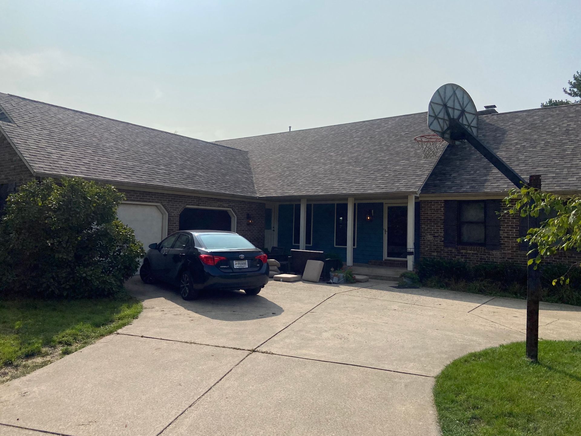 Single-story house with a curved roof, driveway, and a parked black car in front