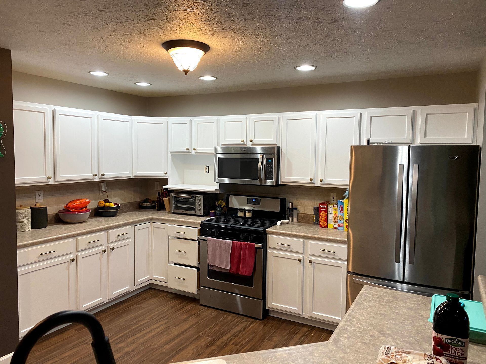 Bright kitchen with white cabinets, stainless steel appliances, and wood-pattern floor