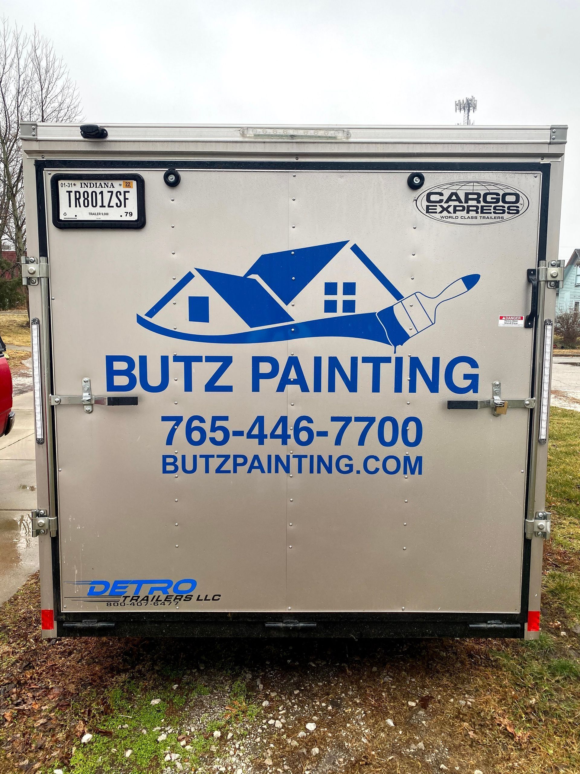 Butz Painting trailer with blue logo and contact info on a silver cargo trailer outdoors