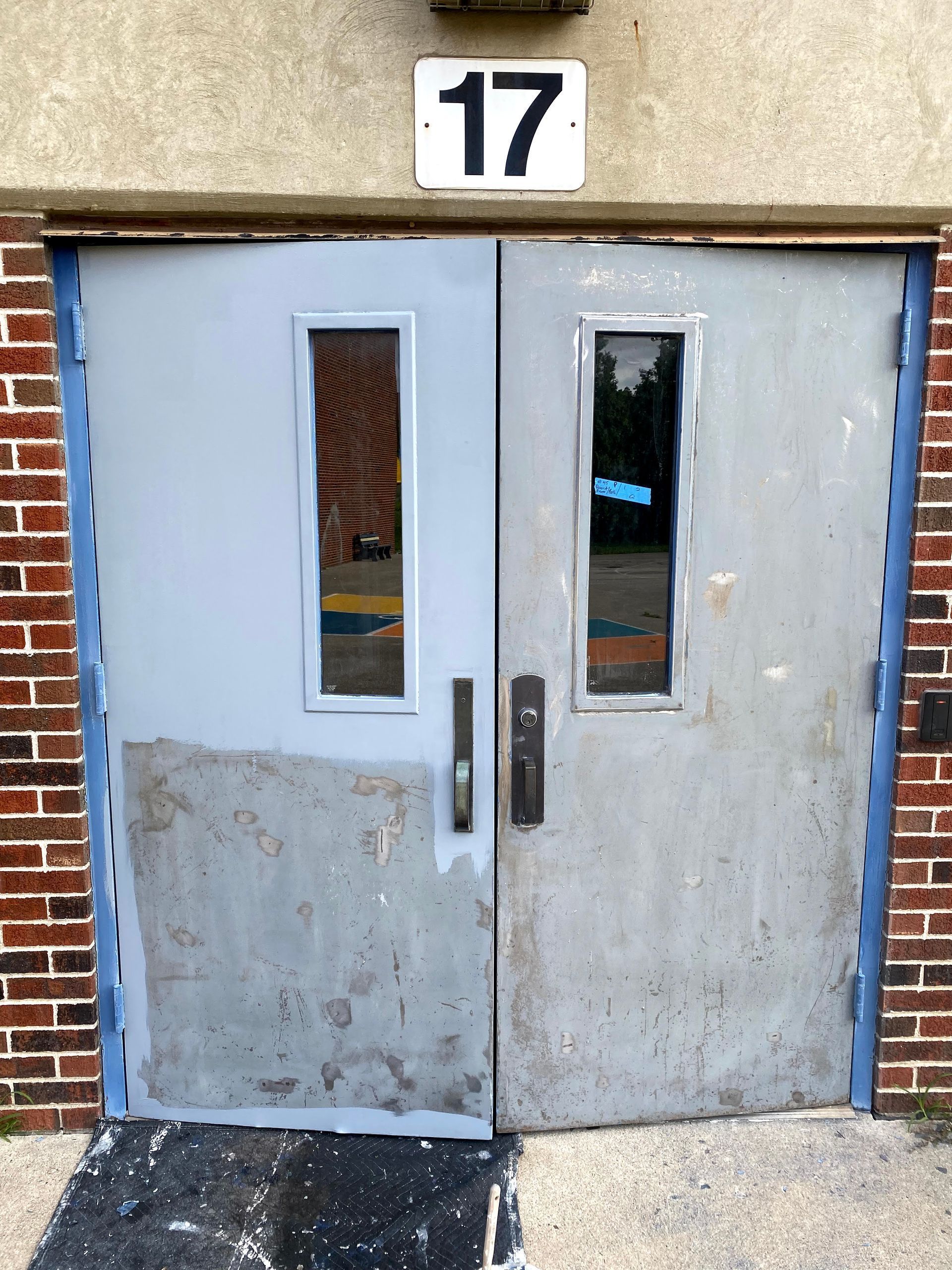 Weathered gray double doors with narrow windows beneath the number 17 entryway