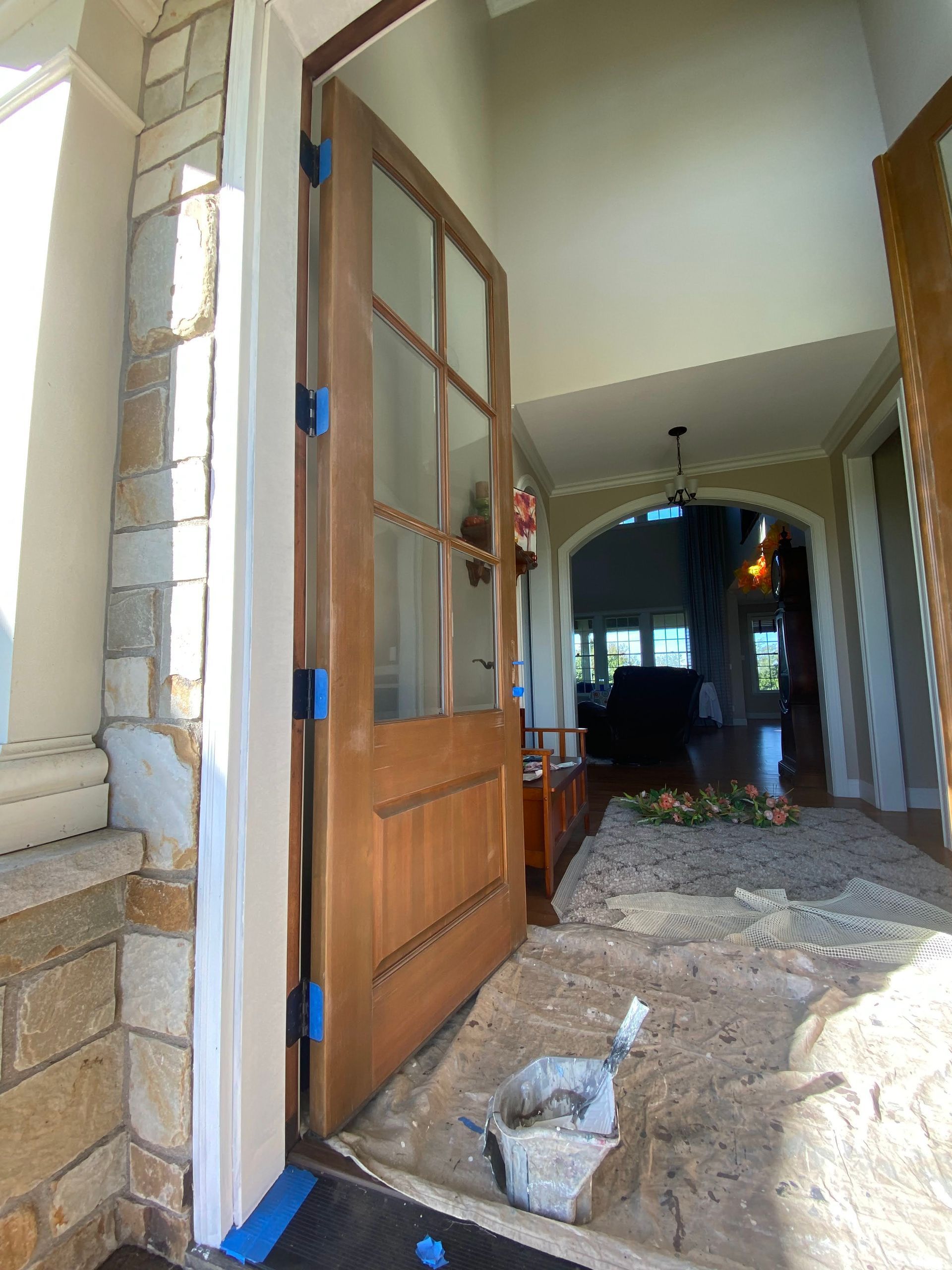 Open front door with glass panels leading into a hallway under construction, with rubble on the floor.