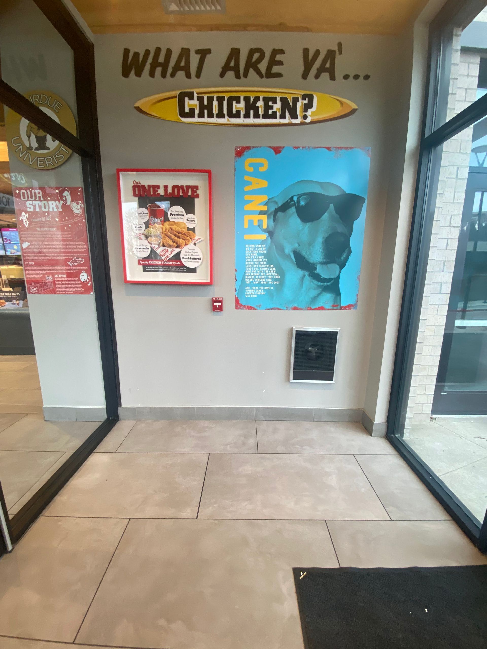 Restaurant entryway with posters and a “What Are Ya… Chicken?” sign above the door