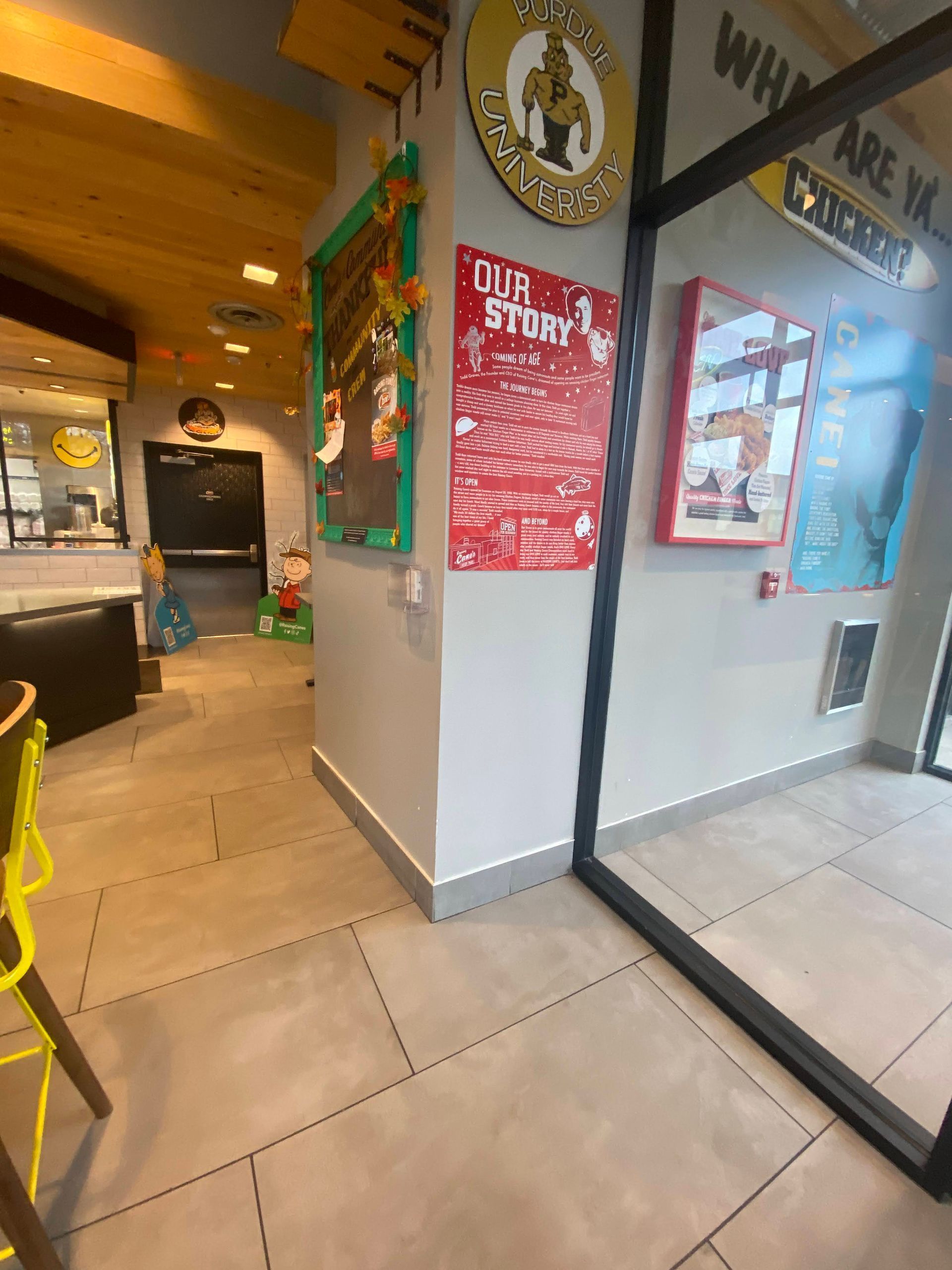 Restaurant interior with colorful wall signs, tiled floor, and a glass partition reflecting the dining area.