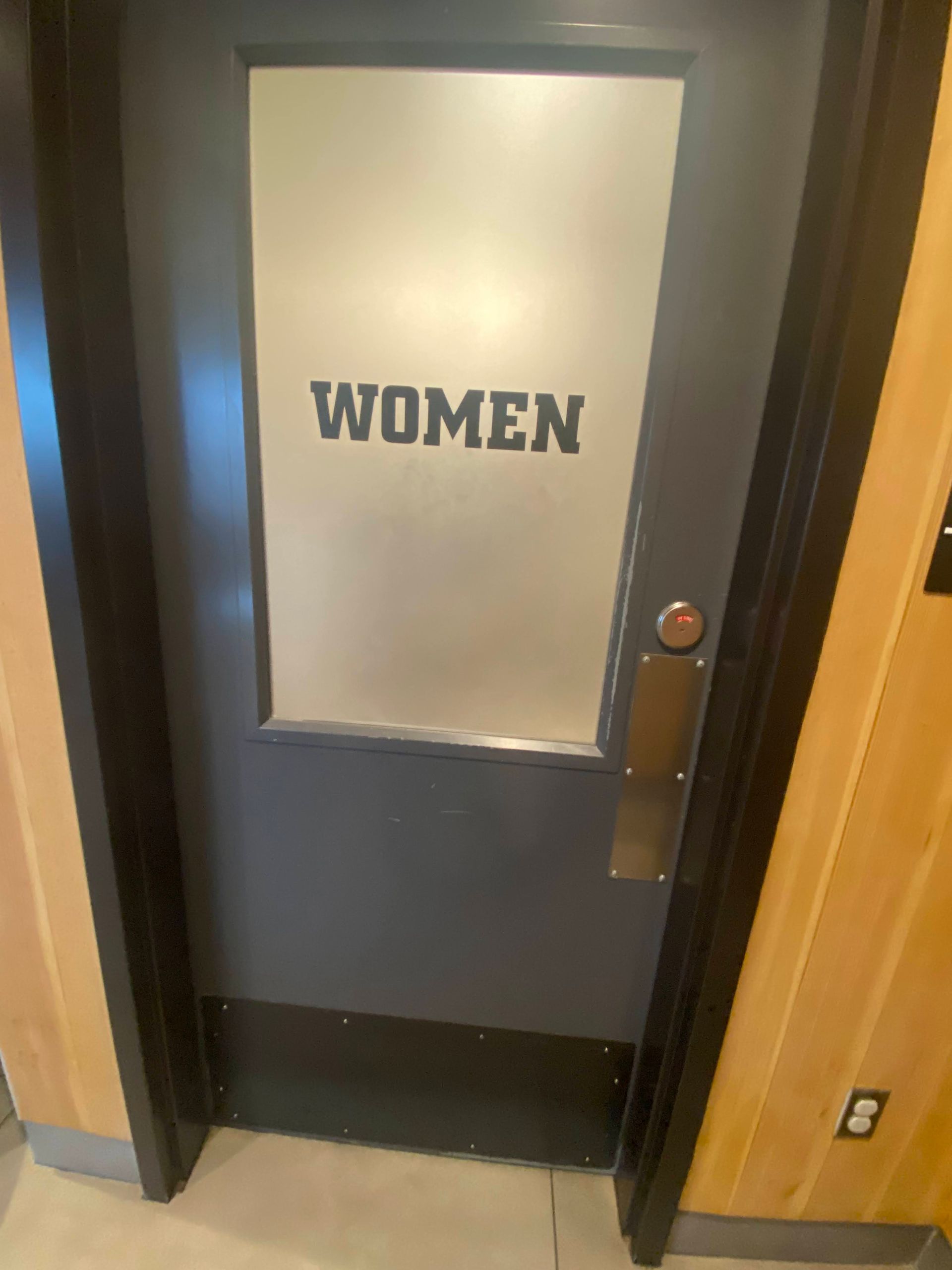 Women’s restroom door with frosted glass panel and dark frame