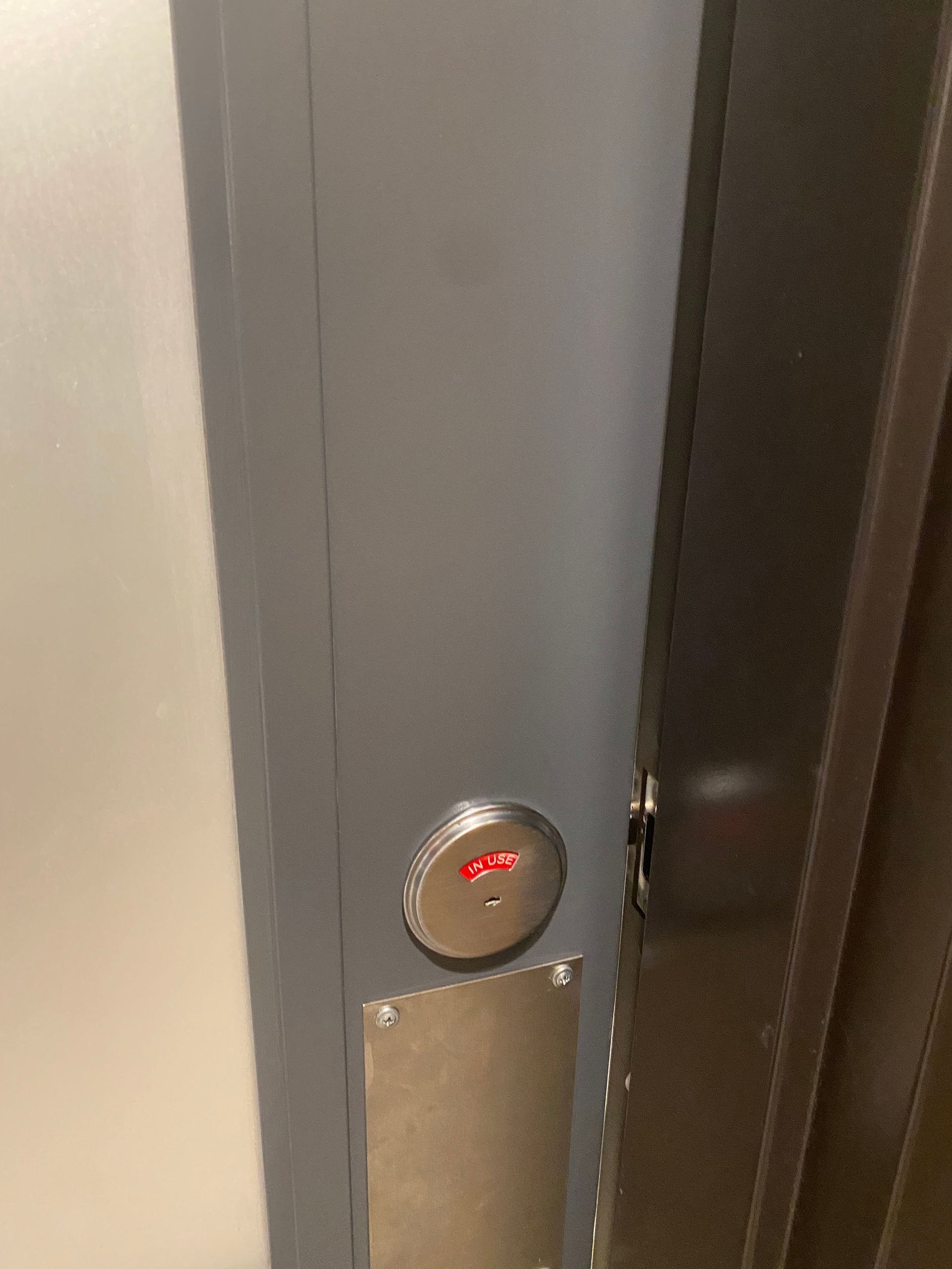Close-up of a wall-mounted elevator call button with a red indicator light.