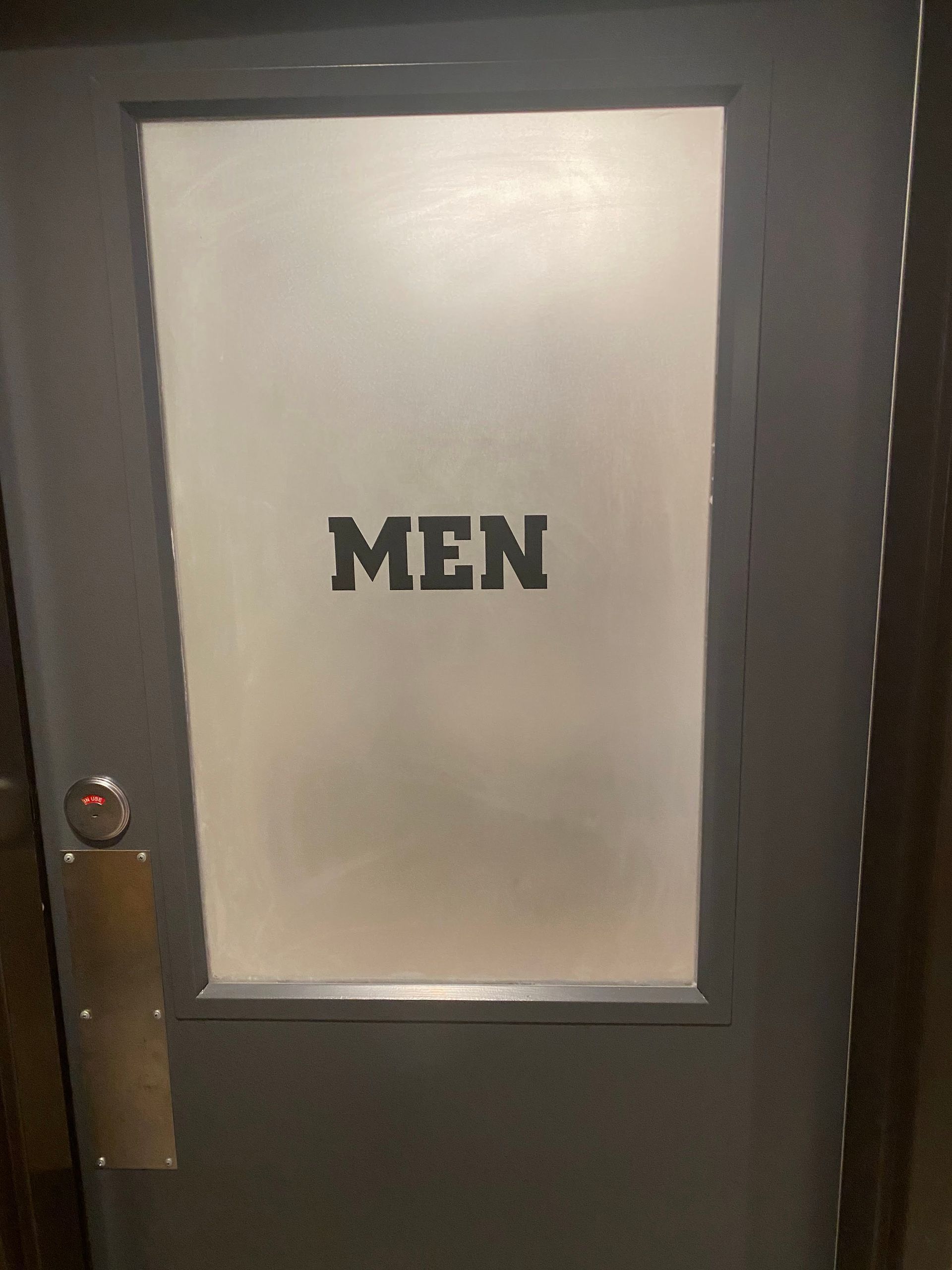 Men's restroom door with frosted glass panel and black sign reading 