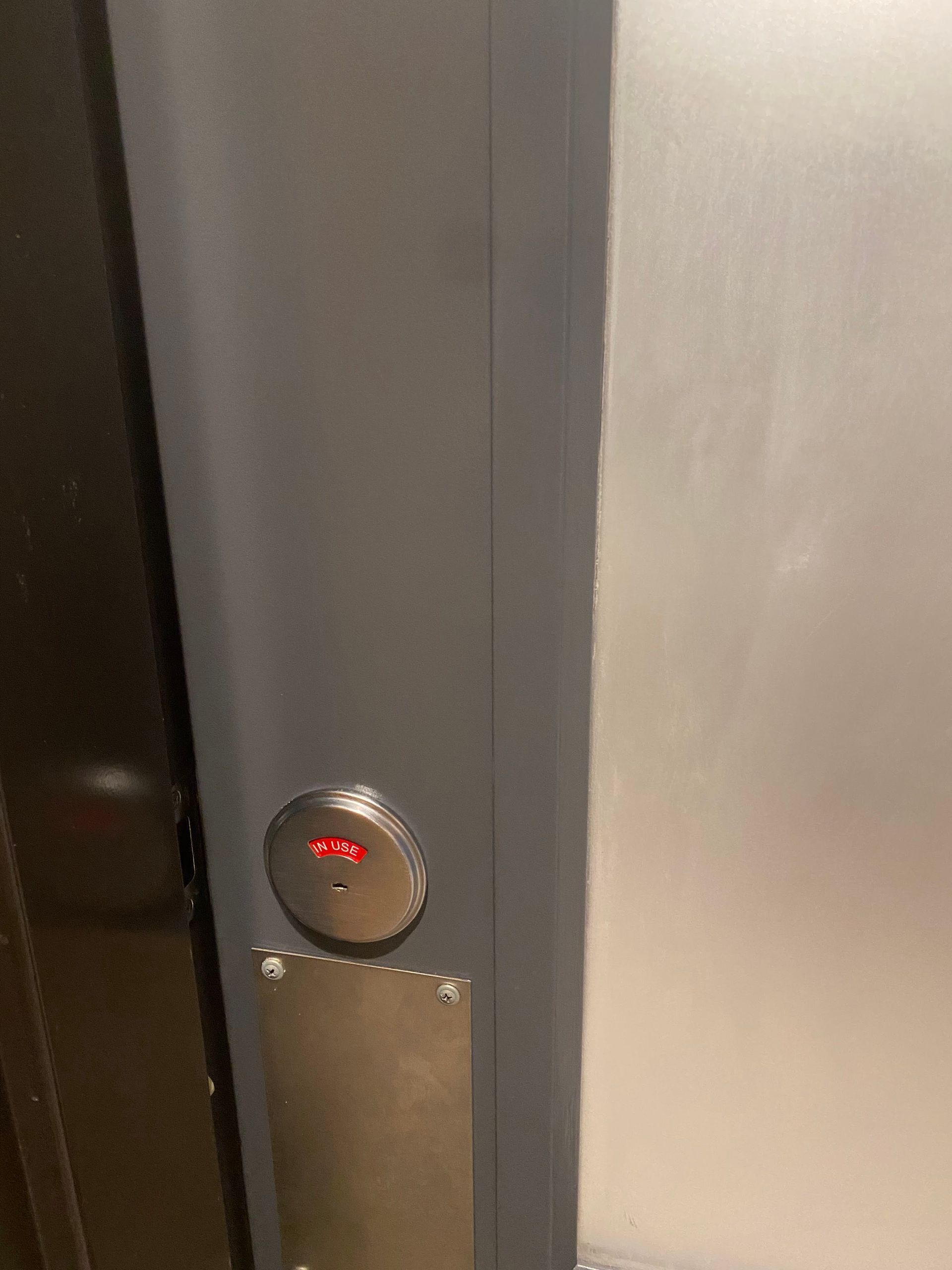Close-up of an elevator panel with a glowing red floor indicator and metallic doors.