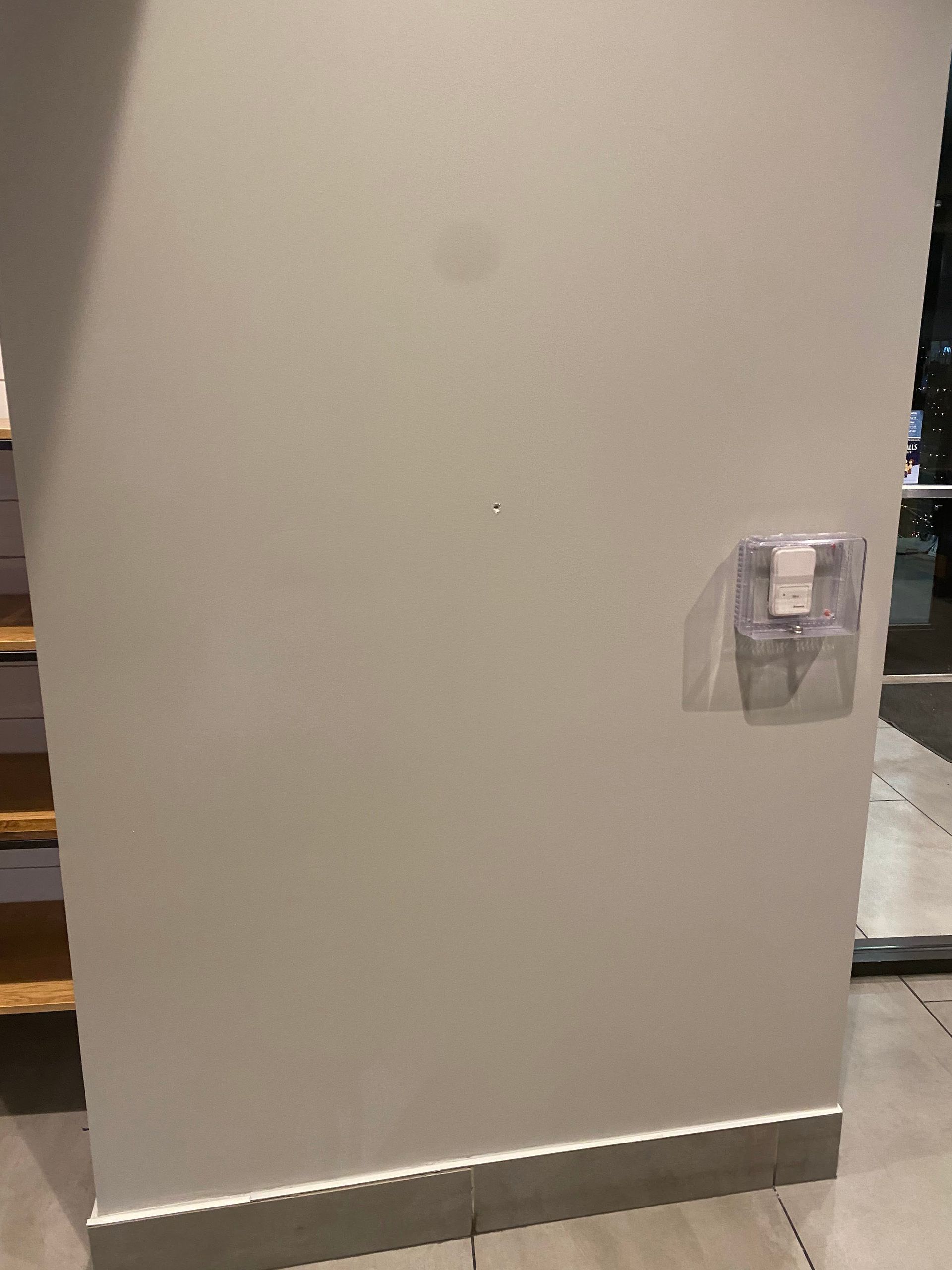 Empty beige wall with a mounted dispenser or control panel near the right side.