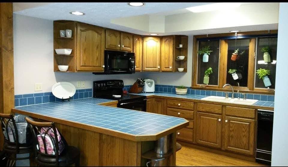 Bright kitchen with blue countertops, wooden cabinets, and a window over the sink